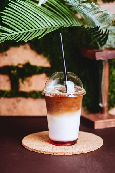 Smoothies and iced coffee in plastic cup on wooden tray and brick wall background in cafe.