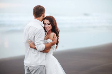 Gün batımı sırasında okyanus plajında yürüyüş zarif muhteşem gelin ve damat.