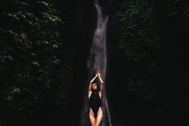 Ormanlardaki şelaleye bakan genç bir kadın..