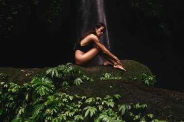 Ormanlardaki şelaleye bakan genç bir kadın..