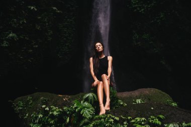 Ormanlardaki şelaleye bakan genç bir kadın..