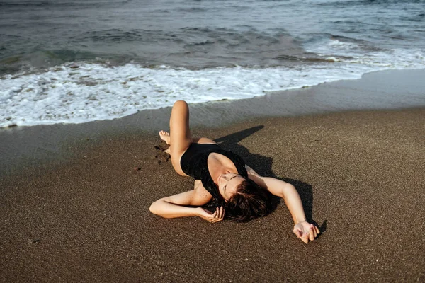 Retrato de una hermosa mujer de moda deportiva en bikini negro posando en verano cerca del océano —  Fotos de Stock