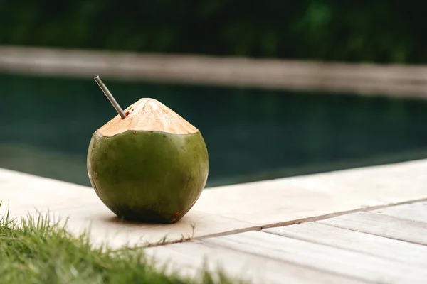 Verse kokosnoot met stro op de rand van een zwembad — Stockfoto