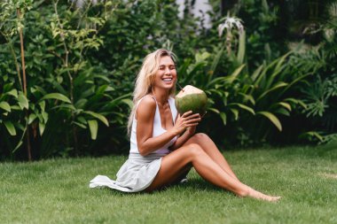 Beyaz elbiseli güzel sarışın kadın Hindistan cevizli tropikal terasta