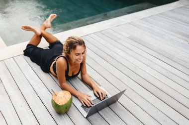 Havuz başında dizüstü bilgisayarla çalışan kadın..