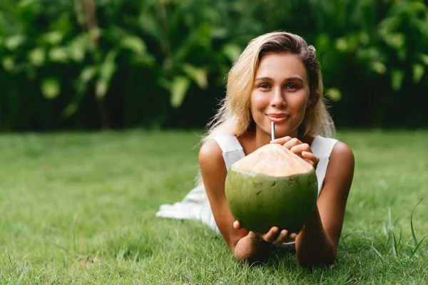 Vacker blond kvinna i vit klänning på den tropiska terrassen med kokos — Stockfoto