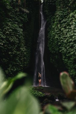Genç kız şelalede banyo yapıyor.