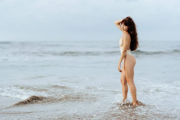 Mavi okyanusun arkasında poz veren bikinili kadın. — Stok fotoğraf
