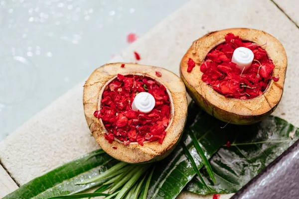 Rozenbloesem, bloemblaadjes in kokosnoot kom, rode bloemen, kaarsen — Stockfoto