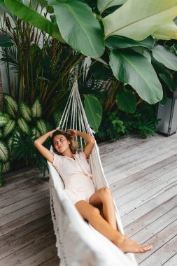 Genç ve güzel bir kadın hamakta dinleniyor.