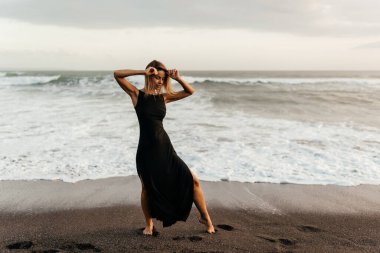 Kumsaldaki kadın, tatil boyunca sakin okyanus doğasının tadını çıkarıyor.