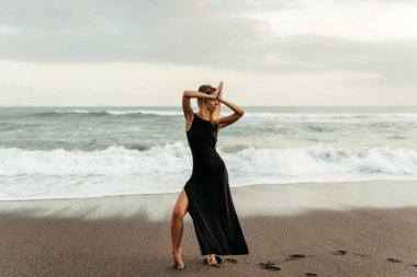 Kumsaldaki kadın, tatil boyunca sakin okyanus doğasının tadını çıkarıyor.