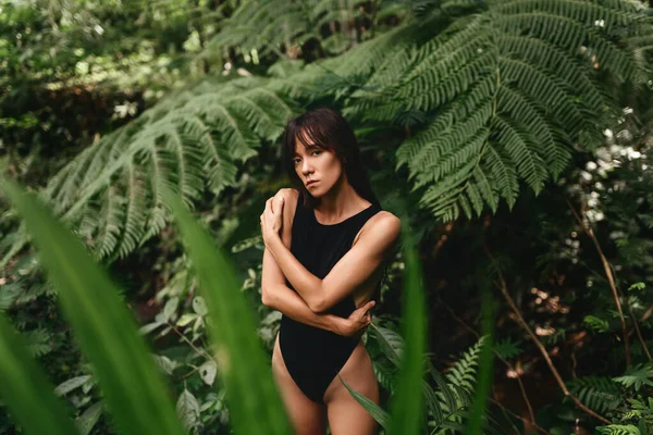 Vonzó fiatal nő a trópusi növények között. — Stock Fotó