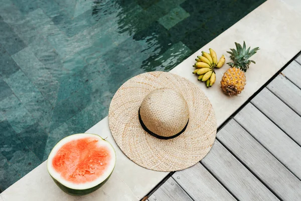 Melancia, abacaxi, banana, chapéu junto à piscina — Fotografia de Stock