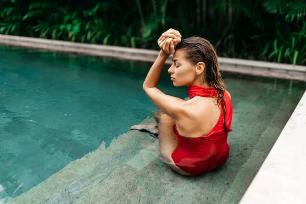Mujer en traje de baño rojo relajante en la piscina — Foto de Stock