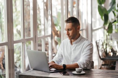 Kafedeki bilgisayarında çalışan genç bir adam.