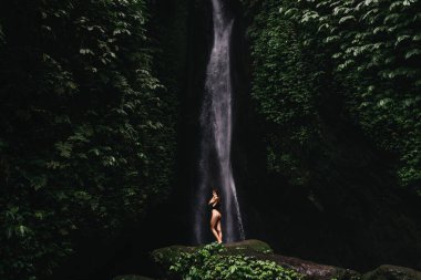 Şelale altında dinlenen güzel genç bir kadın.