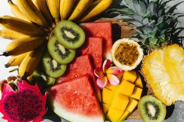 Tropical fruits assortment on a wooden plate. Stone background. — Stock Photo, Image