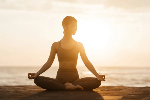 Yoga bij zonsondergang op het strand. vrouw uitvoeren van asanas en genieten van het leven op de oceaan Stockfoto