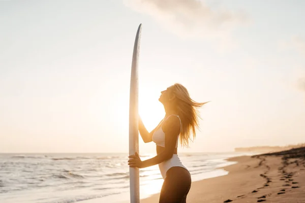 Vacker surfare kvinna på stranden vid solnedgången — Stockfoto