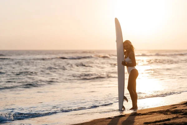 Hermosa mujer surfista en la playa al atardecer —  Fotos de Stock