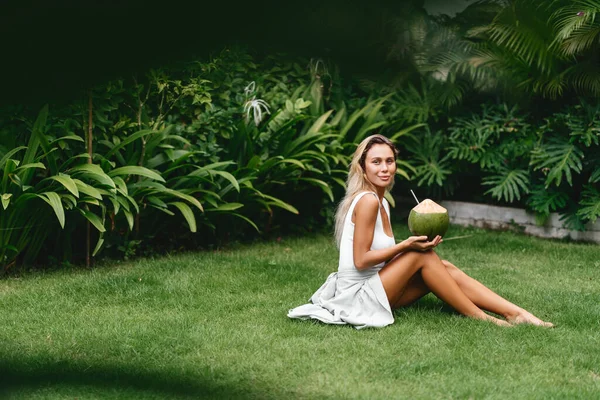 Mulher loira bonita no vestido branco no terraço tropical com coco — Fotografia de Stock