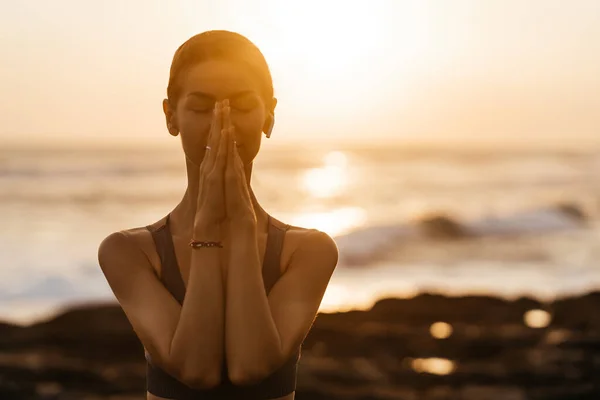 Yoga bei Sonnenuntergang am Strand. Frau führt Asanas durch und genießt das Leben auf dem Ozean — Stockfoto