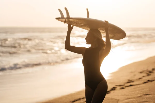 Mulher surfista bonita na praia ao pôr do sol — Fotografia de Stock