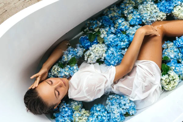 Frau entspannt sich im Bad mit tropischen blauen Hortensien. — Stockfoto