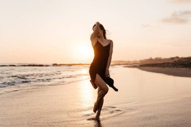 Özgürlük isteyen Çinli kadın plaj günbatımında dans ediyor..