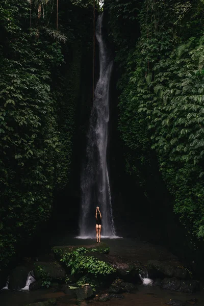 Jovem mulher mochileiro olhando para a cachoeira em selvas. — Fotografia de Stock