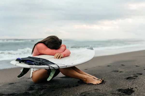 Young attractive surfer woman with white board at sunset on the ocean. Bali Indonesia.