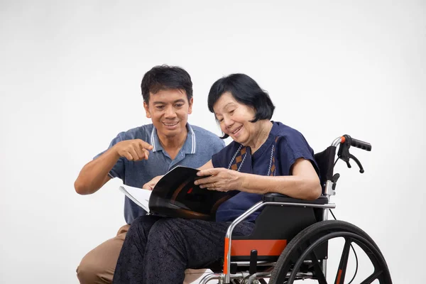Starsza Kobieta Książką Wózku Inwalidzkim Synem Dbać — Zdjęcie stockowe