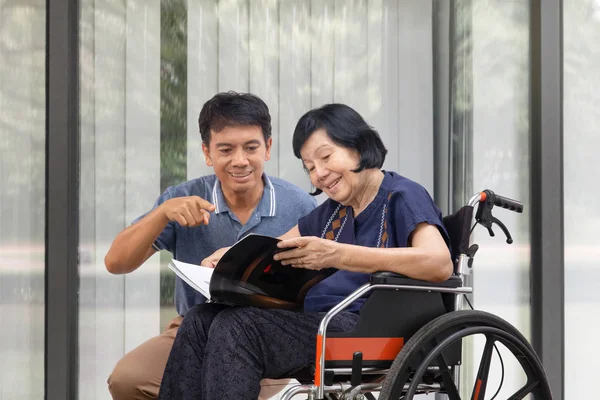 Mujer Mayor Leyendo Libro Silla Ruedas Con Hijo Cuidar — Foto de Stock