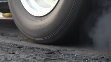 Sürüklenen yarış arabası yarışa hazırlanırken lastiklerini yakıyor.