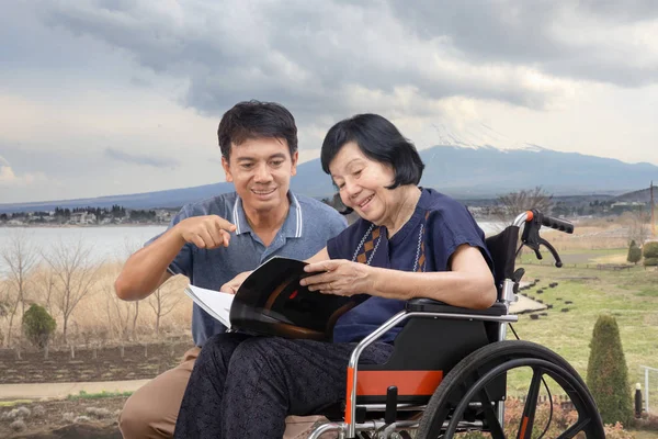 Bejaarde Vrouw Lezen Van Een Boek Rolstoel Met Haar Zoon — Stockfoto
