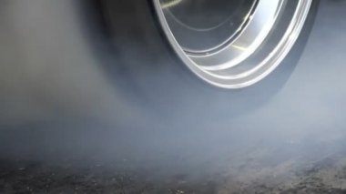 Sürüklenen yarış arabası yarışa hazırlanırken lastiklerini yakıyor.