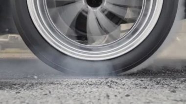 Sürüklenen yarış arabası yarışa hazırlanırken lastiklerini yakıyor.