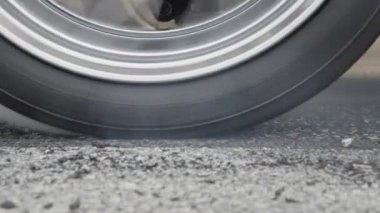 Sürüklenen yarış arabası yarışa hazırlanırken lastiklerini yakıyor.