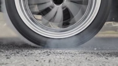 Sürüklenen yarış arabası yarışa hazırlanırken lastiklerini yakıyor.