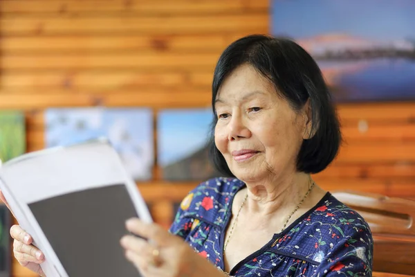 Elderly Asian Woman Smiling While Reading Magazine — Stock Photo, Image