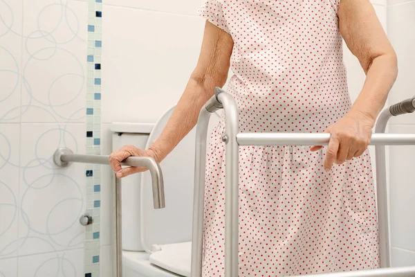 老妇人手持扶手在洗手间 — 图库照片