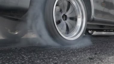 Sürüklenen yarış arabası yarışa hazırlanırken lastiklerini yakıyor.