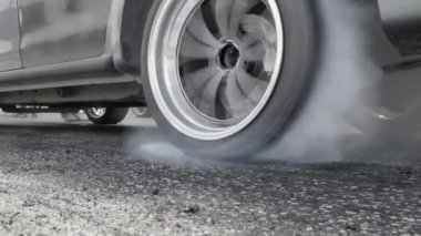 Sürüklenen yarış arabası yarışa hazırlanırken lastiklerini yakıyor.