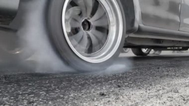 Sürüklenen yarış arabası yarışa hazırlanırken lastiklerini yakıyor.