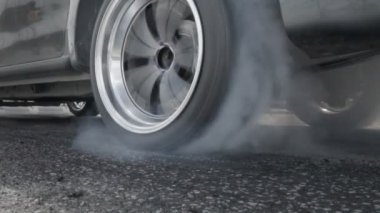 Sürüklenen yarış arabası yarışa hazırlanırken lastiklerini yakıyor.
