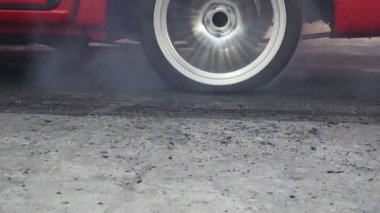 Sürüklenen yarış arabası yarışa hazırlanırken lastiklerini yakıyor.