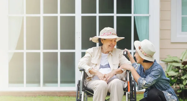 Seniorin sitzt mit Tochter im Rollstuhl im Hinterhof — Stockfoto