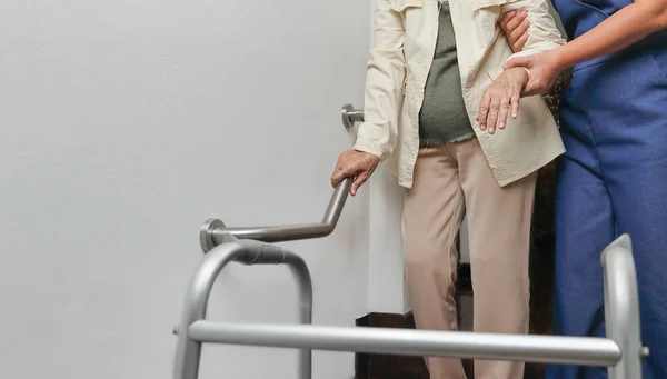 Seniorin hält sich mit Betreuer am Geländer fest — Stockfoto