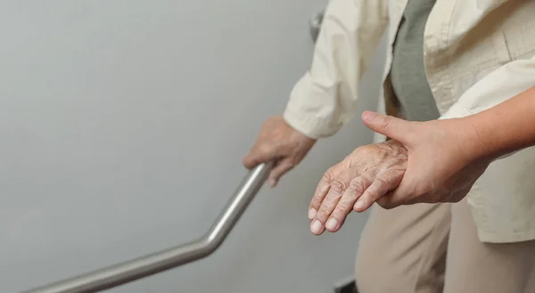 Seniorin hält sich mit Betreuer am Geländer fest — Stockfoto
